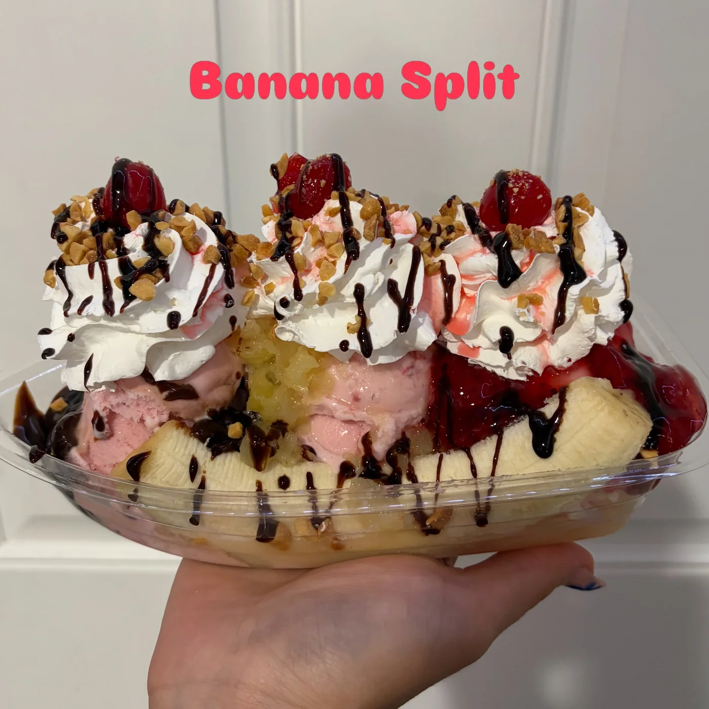 Banana split with ice cream, whipped cream, cherries, nuts and sauces