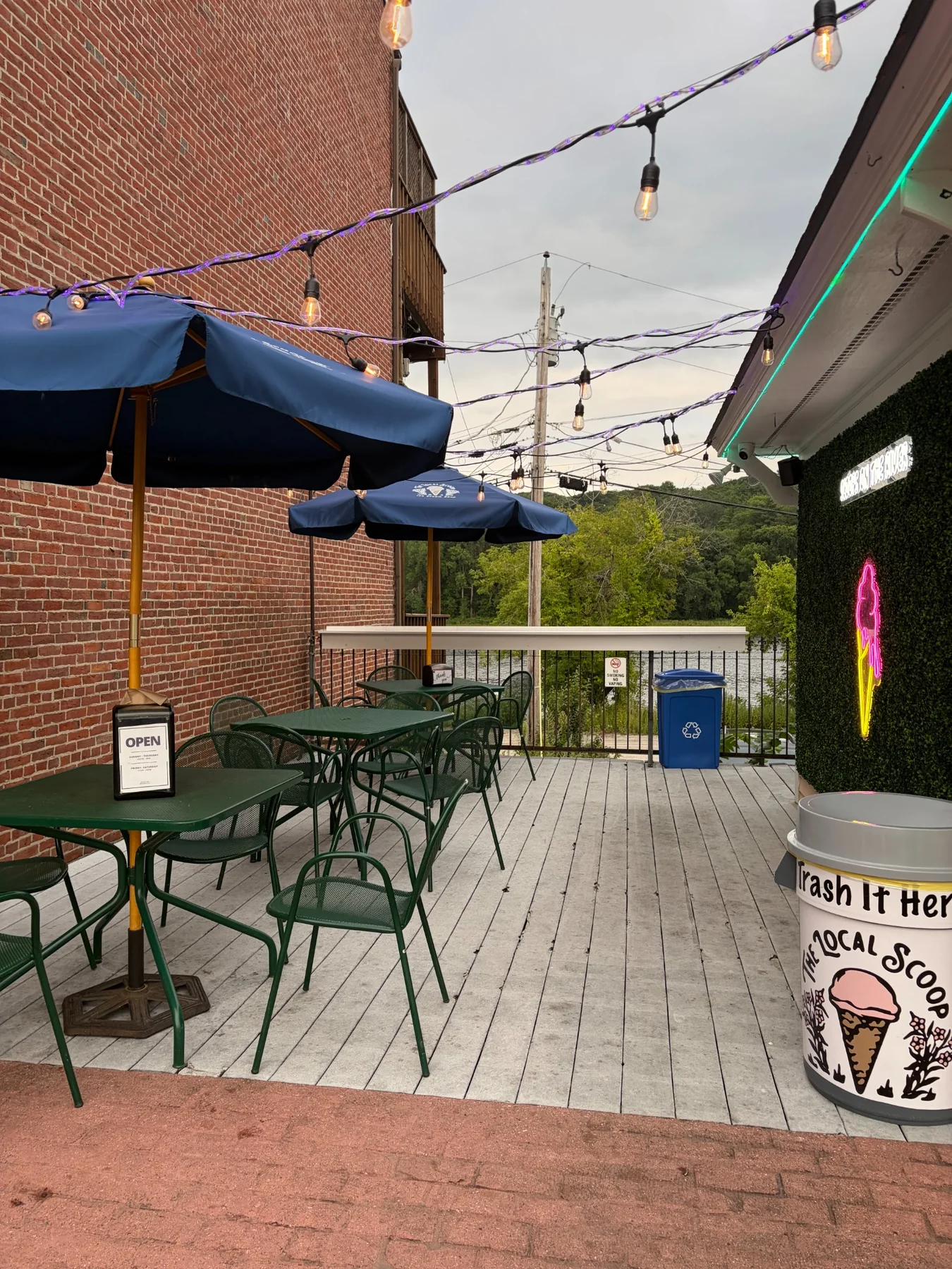 The Local Scoop deck with tables, umbrellas, string lights and river view